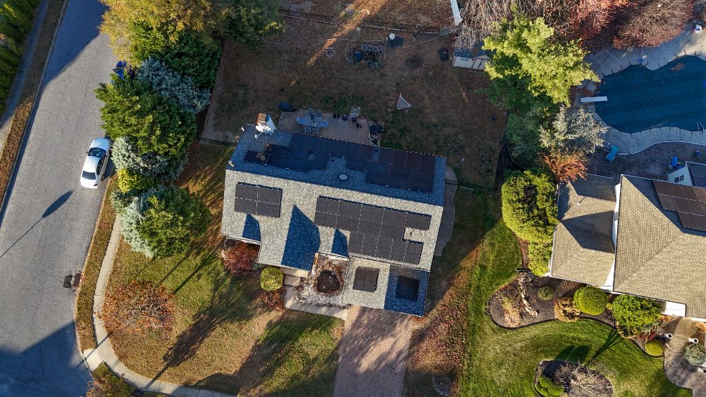 Aerial fall view of a home with solar panels installed along a tree-lined street
