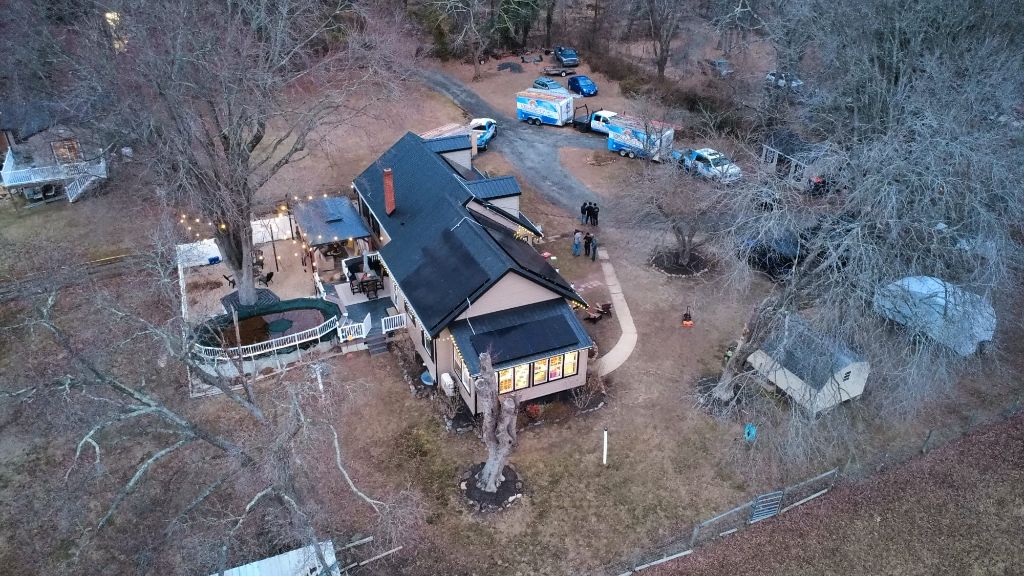Aerial dusk view of a home with solar panels installed and lights on inside