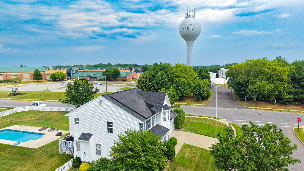Aerial view of a home with solar panels installed near a municipal water tower